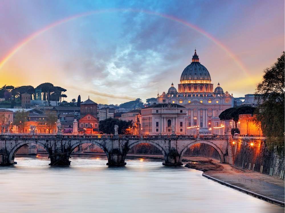 Veduta serale di Roma con la Basilica di San Pietro, un ponte e un arcobaleno