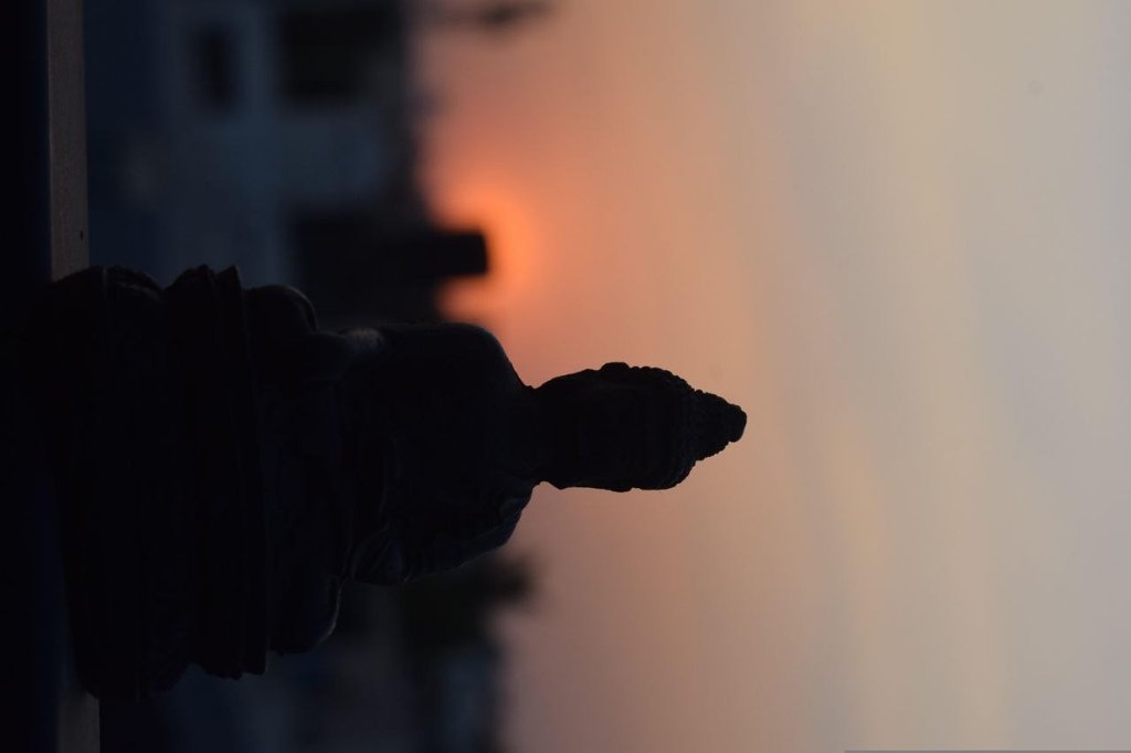 Statua di Buddha in silhouette al tramonto con il sole sullo sfondo
