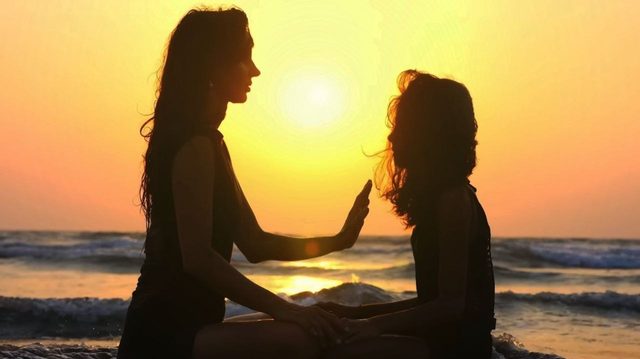 Donna e bambina in controluce sulla spiaggia al tramonto